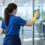 Professional commercial cleaner cleaning a glass partition